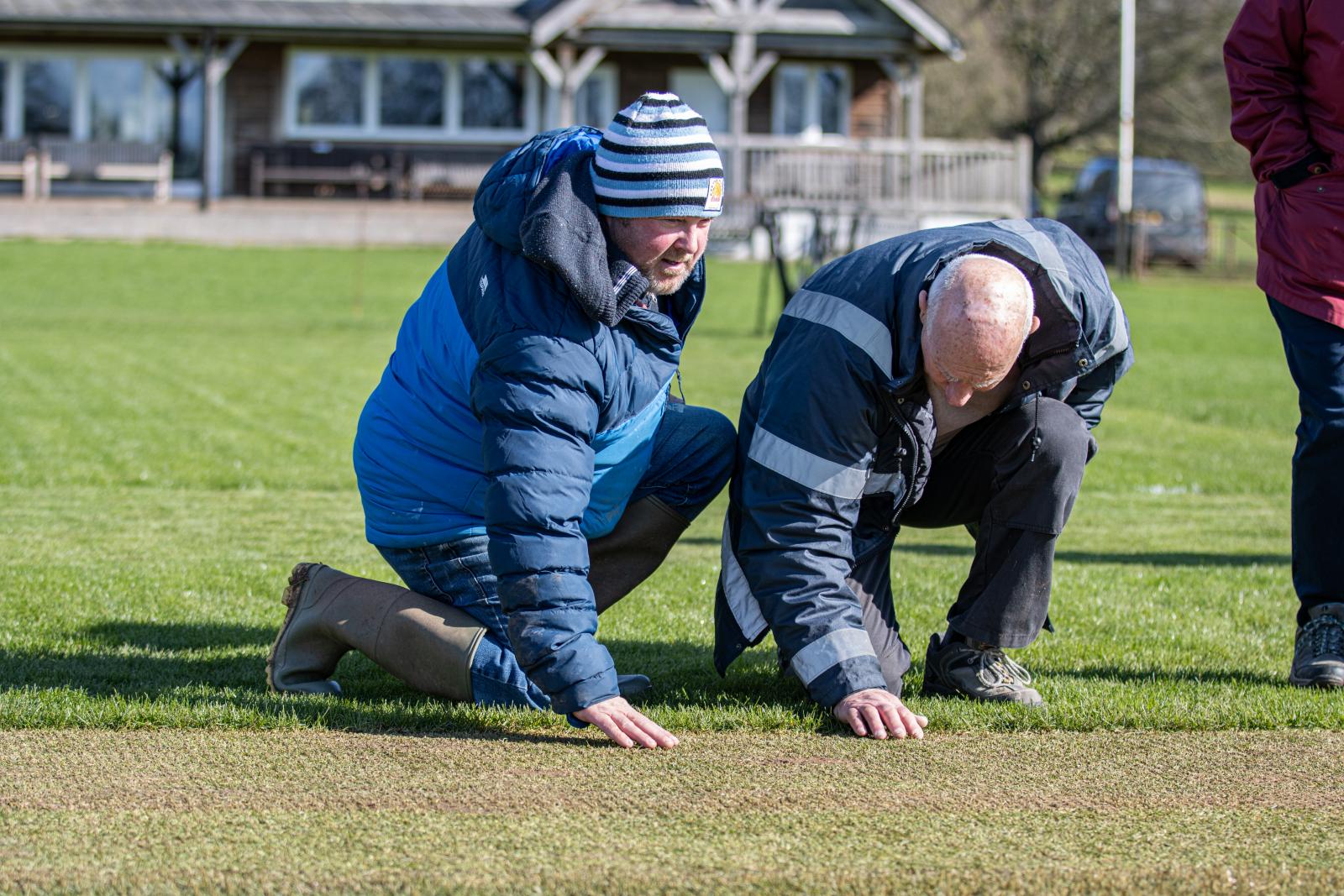 Groundskeepers observe the newly laid strips of hybrid pitch at Heathcoat CC.