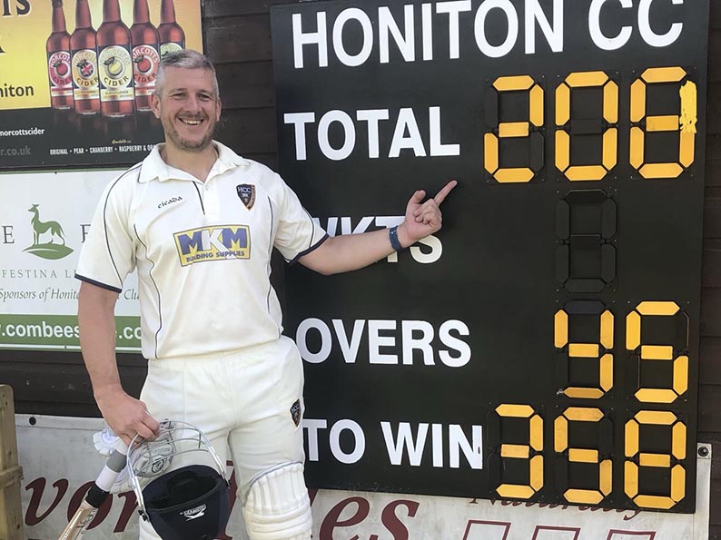 Dave Haysom poses by the scoreboard after his history making innings