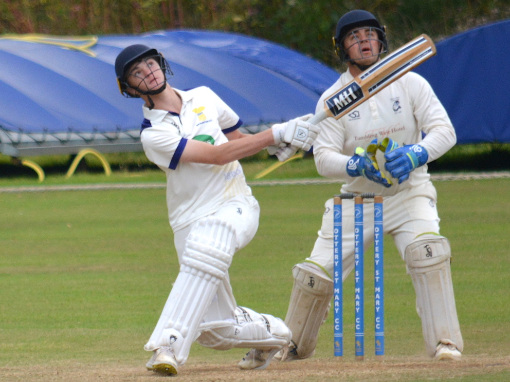 Ottery keeper Alex Clements can only watch in admiration as Braunton's Joe Mullins smashes the bowling for six