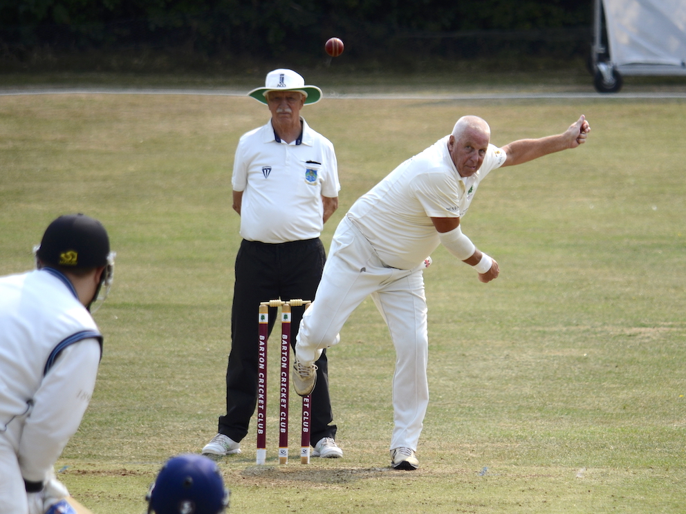 Barton's veteran spinner Dave Cadwallader bowling against Kenn under the watchful scrutiny of umpire Steve Porter